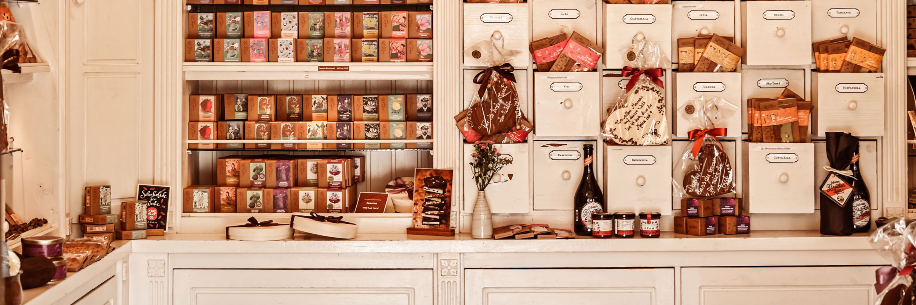 Schokolade und Pralinen schön angeordnet in einem alten, weißen Apothekerschrank.